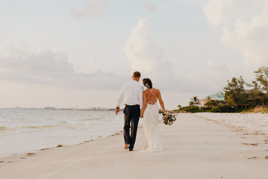Perfect Sunset Destination Beach Wedding with Beautiful Bride and Groom Walking Down the Coastline