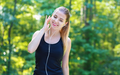 Athletic young woman with headphones on a bright summer day in the forest