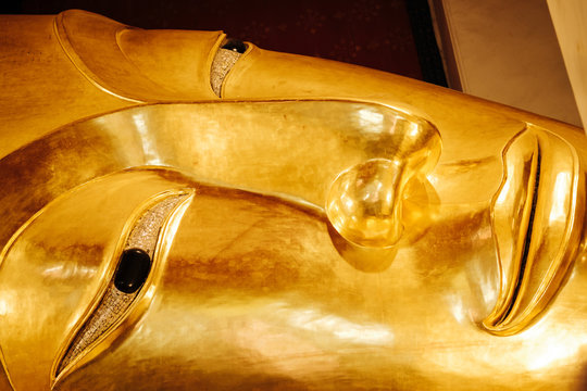 Close up image on face of old golden reclining buddha at Wat Phra Non Chakkrasi Worawihan, Singburi Province, Thailand