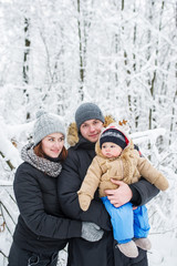 Fototapeta na wymiar Happy family of three against the background of snow-covered trees.
