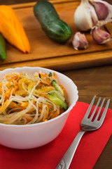 Rice noodle salad with fresh vegetables in a white bowl.