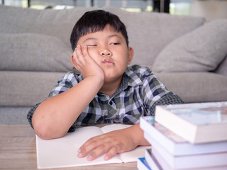 Cute asian children is bored and tired with doing homework on desk in the room. education concept.