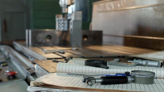 A private workshop for working with metal parts, in the background a drilling machine drills a hole in the pulley, on the table lie measuring instruments