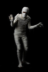 Fototapeta na wymiar Studio shot portrait of young man in costume dressed as a halloween cosplay of scary mummy pose like a clamber acting on isolated black background.