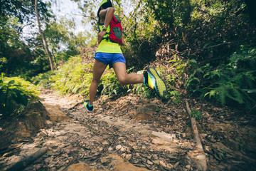 Young woman trail runner running on tropical forest trail