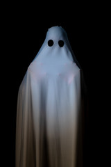 Someone covered with white cloth with big black eyes on black background look like ghost in night....