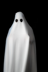 Someone covered with white cloth with big black eyes on black background look like ghost in night....