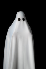 Someone covered with white cloth with big black eyes on black background look like ghost in night. Concept for funny playing in halloween festival