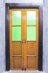 Vintage wooden door with Stained glass on the cement wall