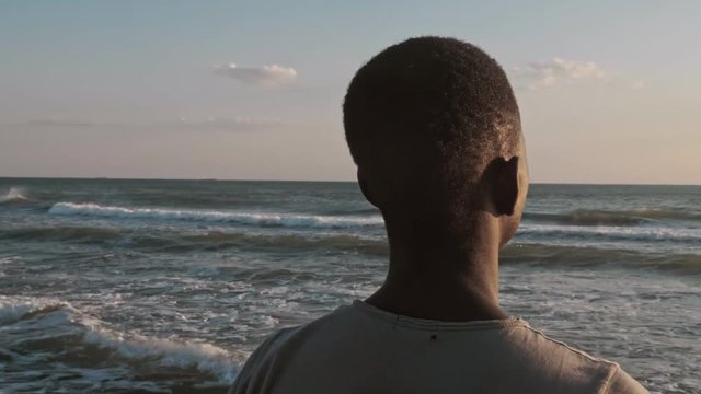 Missing home,Africa.Lonely young african migrant contemplating the ocean