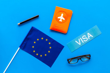 Schengen visa. Visa to Europe concept. Text visa near passport cover and european flag on blue background top view