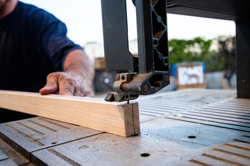 carpenter cutting plank with saw