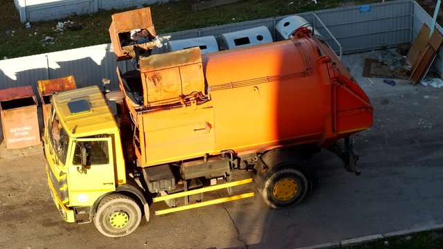 A garbage truck cleans garbage cans in the courtyard of a residential area from garbage and takes it to landfill, dumpster