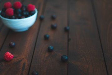 Fresh berries in a bowl on a dark brown wooden table