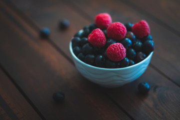 Fresh berries in a bowl on a dark brown wooden table