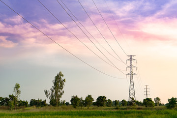 distant high voltage tower on the field sunset scene