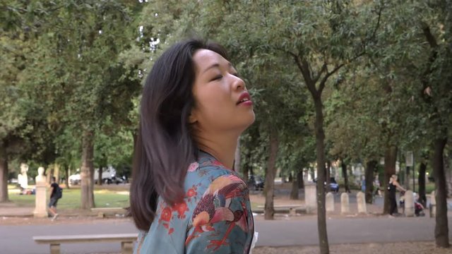 pensive sensual asian woman walking in the park-slow motion