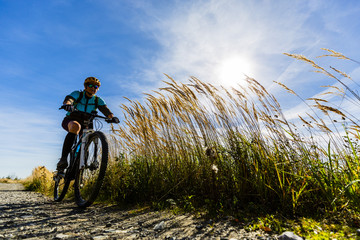 Cycling, mountain bikeing woman on cycle trail in autumn forest. Mountain biking in autumn landscape forest. Woman cycling MTB flow uphill trail.