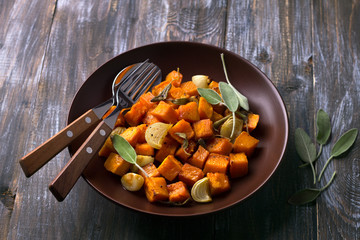 Baked pumpkin with onions, garlic and sage on a wooden table, selective focus. delicious healthy homemade food