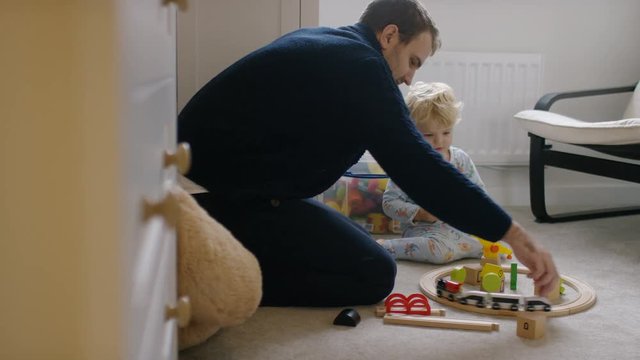 Father and son in a bedroom playing with a toy train set