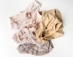 Top view of beige and neutral coloured messy pile of underwear on white background