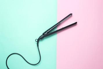 Hair straightener on pastel background. Top view. Minimalism.