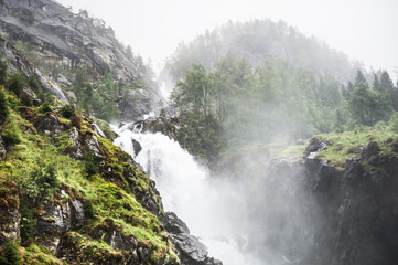 Waterfall in the mountains in foggy morning, Norway.