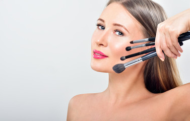 Fototapeta premium Beautiful woman holding makeup brushes near her face - isolated on white background