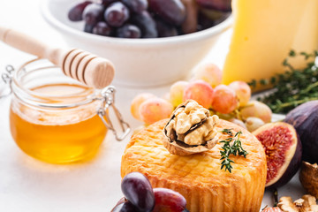 Cheese plate served with grapes, jam, figs, crackers and nuts on a background.