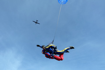 Naklejka na ściany i meble Tandem skydiving. Happy girl and her instructor are n the sky.