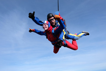 Fototapeta na wymiar Tandem skydiving. Happy girl and her instructor are n the sky.