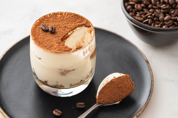 Delicious Italian dessert tiramisu, chocolate, cocoa and coffee beans on a black background. Copy space.