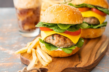 Street food, fast food. Homemade juicy burgers with beef, cheese and spinach on the wooden board.