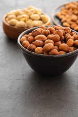 Naklejka na ściany i meble Assorted nuts in bowls on a black background. Copy space.