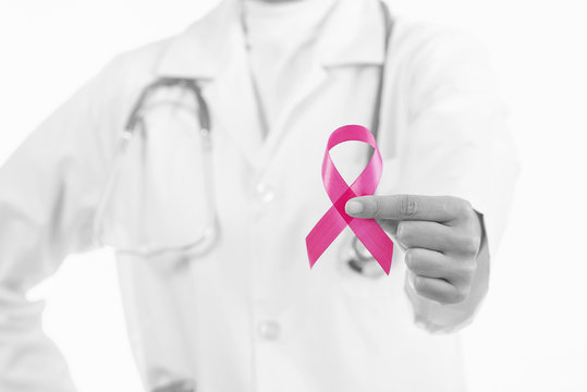 Doctor woman holding pink ribbon, supporting symbol of breast cancer awareness and international women day campaign.