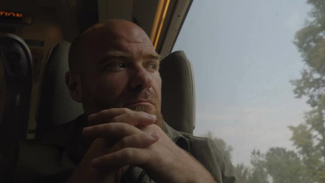 Thoughtful handsome young man on train,looking out window