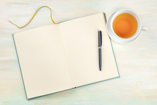 A Photo Of An Open Journal With A Pen And A Cup Of Tea, Shot From Above, On A Light Background With Copy Space