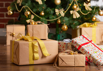 New Year's gifts in designer paper and bright ribbons are under the Christmas Tree on the floor on the eve of the New Year. Close-up