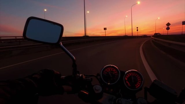 Biker driving a motorcycle rides in highway in sunrise. First-person view