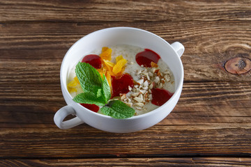 Healthy breakfast - oatmeal with dried apricots, almond and strawberry jam