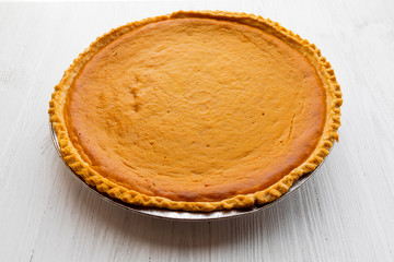 Fresh baked pumpkin pie over white wooden background