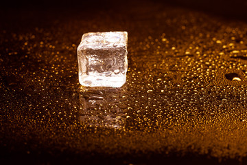 Golden ice cubes reflection on black table.