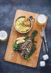 Delicious baked flatfish with potato gratin and beer, top view.