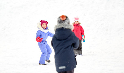 childhood, leisure and season concept - group of happy little kids in winter clothes playing outdoors