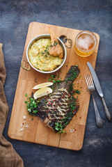Delicious baked flatfish with potato gratin and beer, top view.