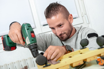young handyman using electric drill, DIY at home
