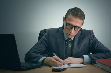 Serious businessman is working with documents and is sitting by the table.