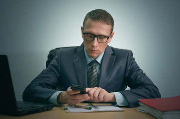 Businessman counts on a calculator and is sitting by the office table.