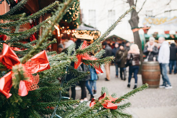 Christmas tree or fir branches in the foreground. The Christmas market in Germany is blurred in the...