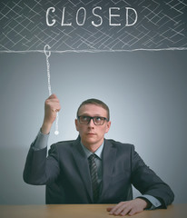 Businessman closes his office with a sign that says "closed". Businessman is closing his company and leave market.